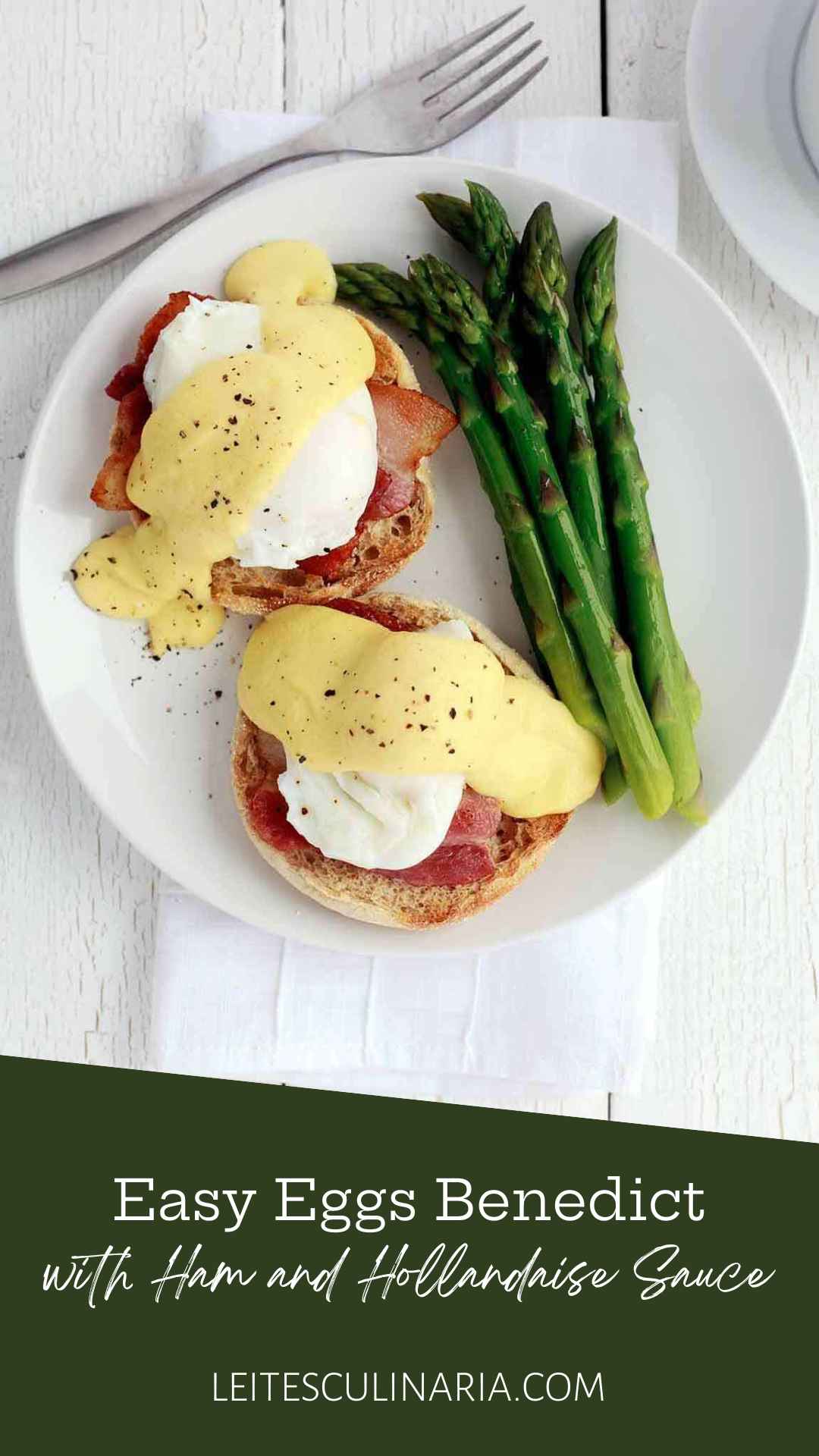 Two eggs Benedict with ham and Hollandaise sauce on a white plate with spears of asparagus.