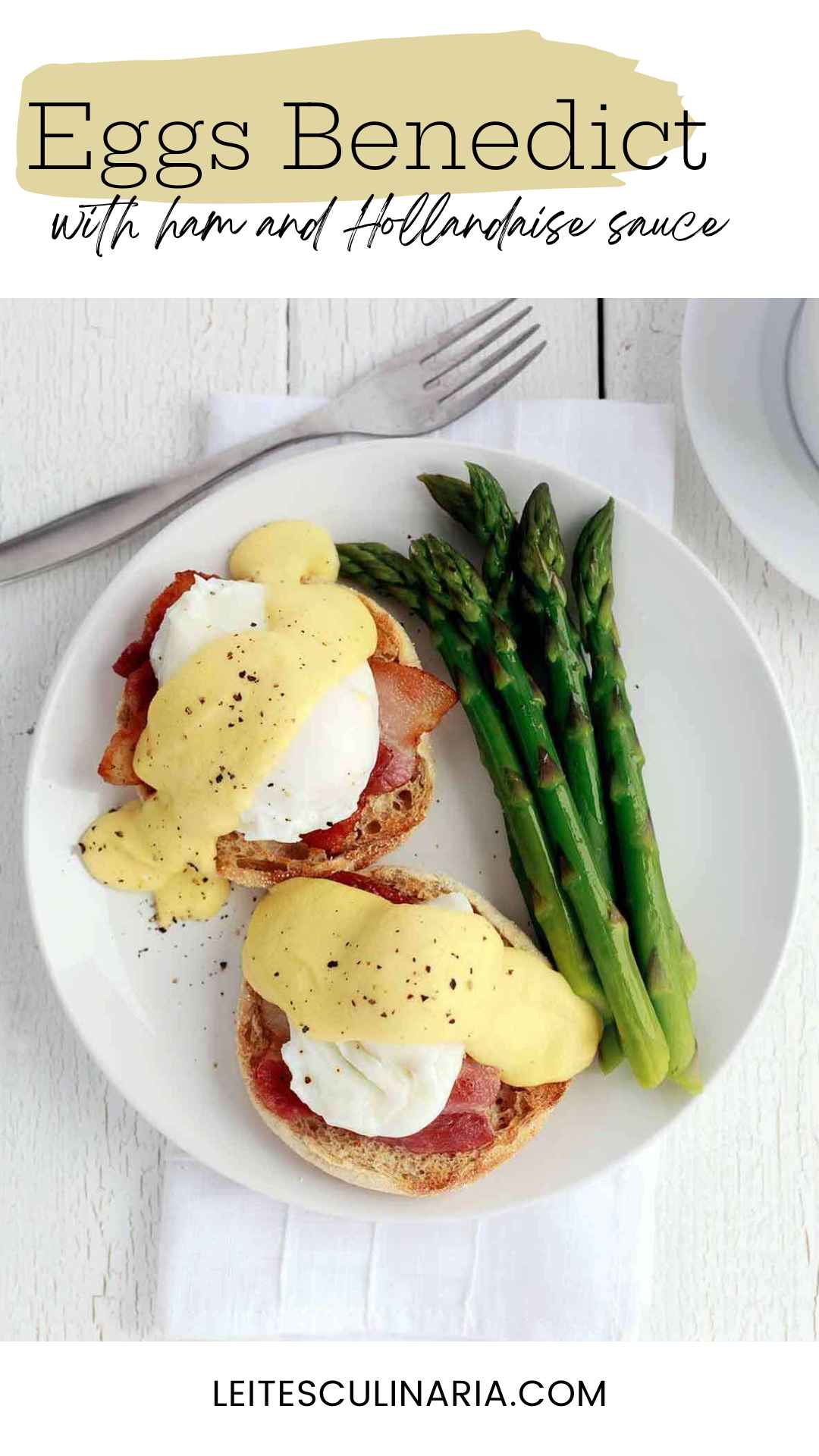 Two eggs Benedict with ham and Hollandaise sauce on a white plate with spears of asparagus.