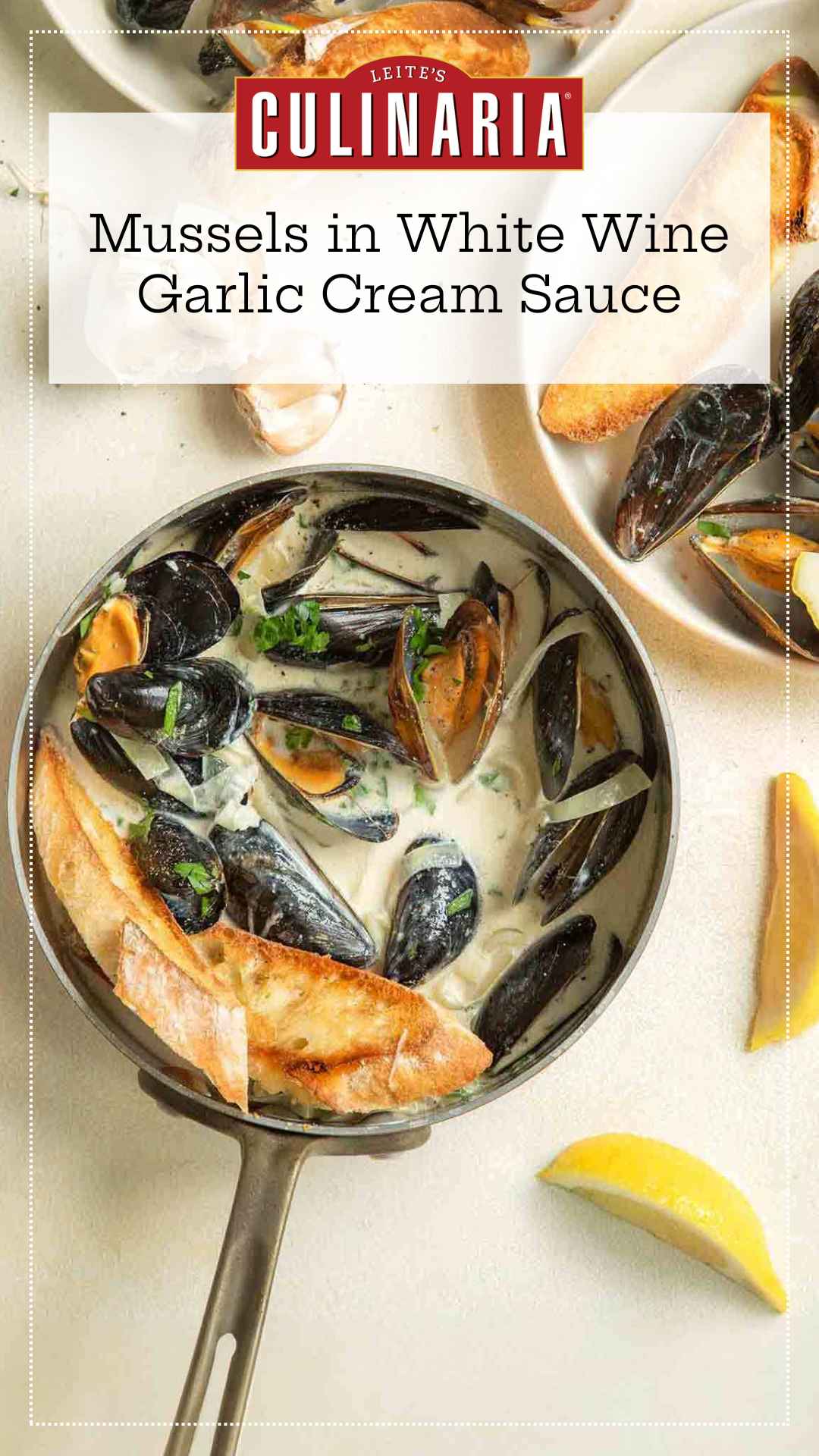 A skillet filled with steamed mussels in a creamy garlic white wine sauce with toasted bread and lemon wedges on the side.