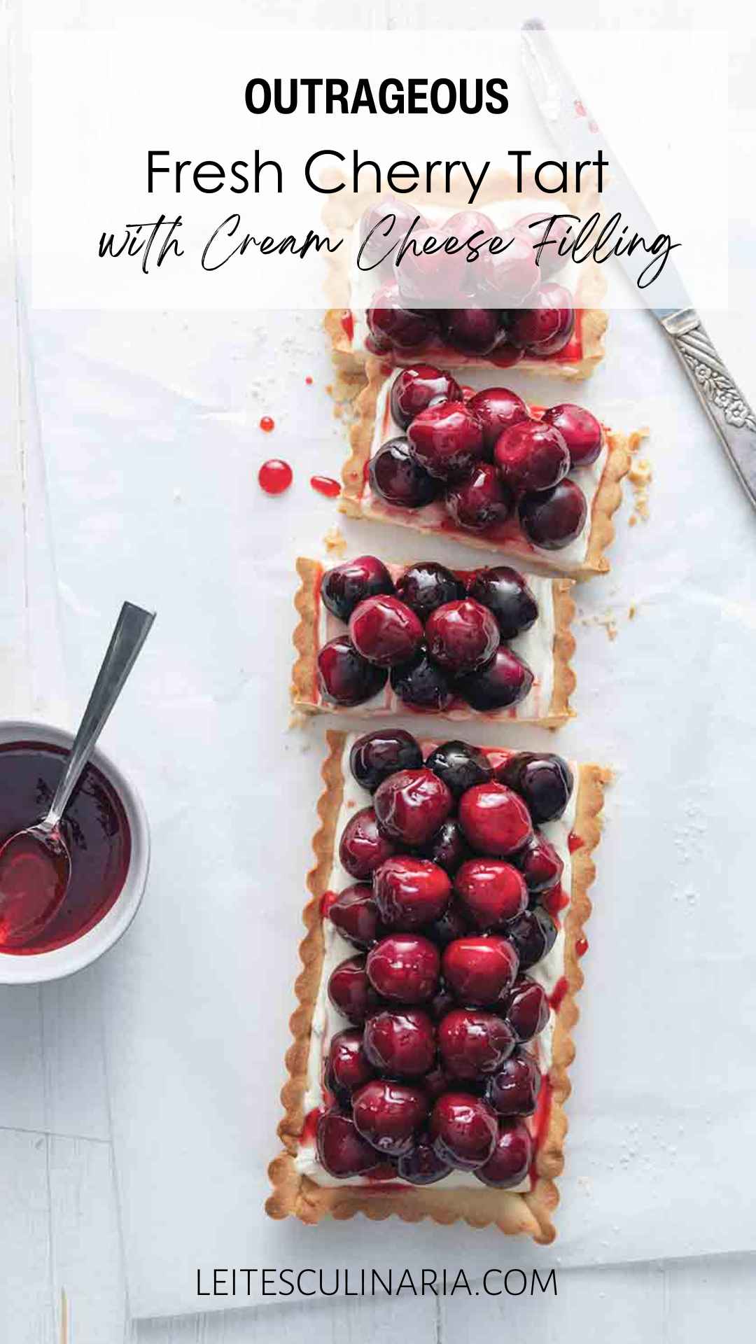 A rectangular tart filled with cream cheese filling and topped with fresh cherries cut into several pieces.