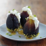 Three figs filled with ricotta cheese and topped with honey on a plate.