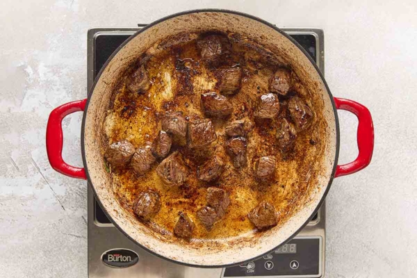 Cubes of browned beef in a cast iron skillet.