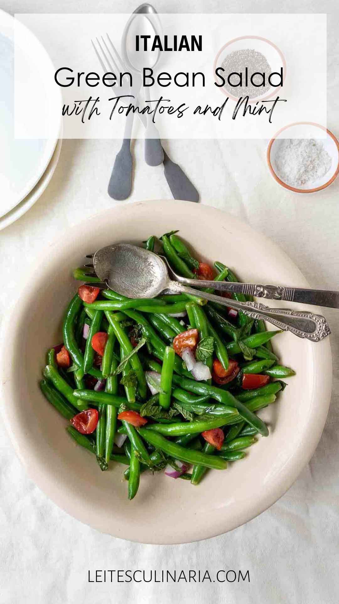A bowl of green bean salad with mint, red onion, and tomatoes.