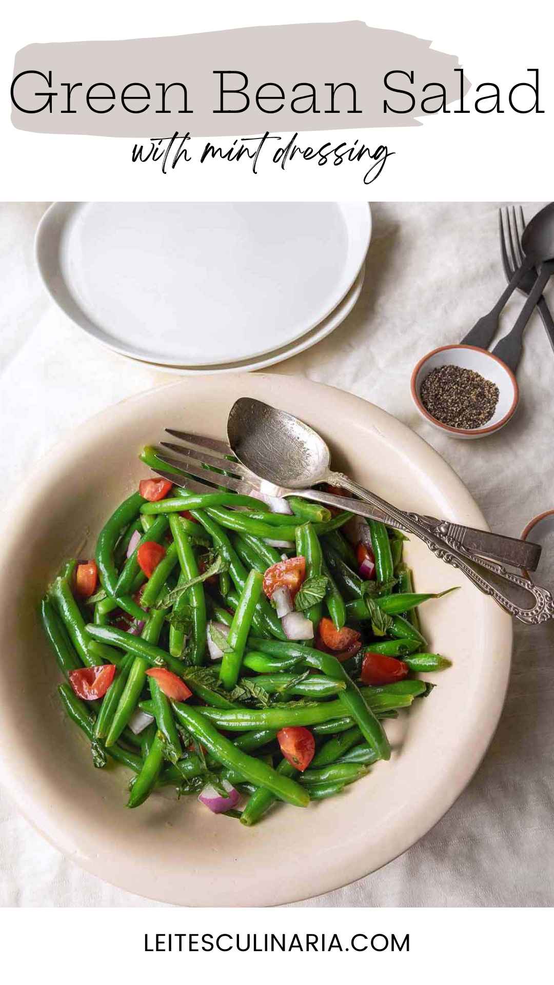A bowl of green bean salad with mint, red onion, and tomatoes.