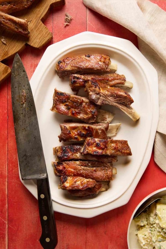 A platter of pressure cooker ribs cut into individual ribs, with a carving knife on the side.