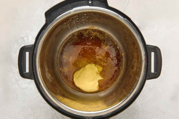 Liquid and Dijon mustard in the bottom of an Instant Pot.