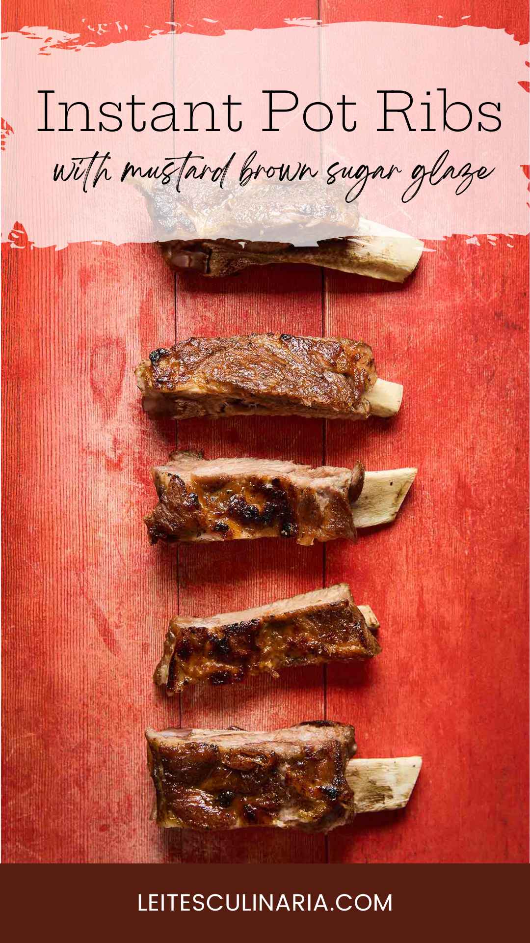 Five individual cooked spare ribs lined up on a red wooden board.