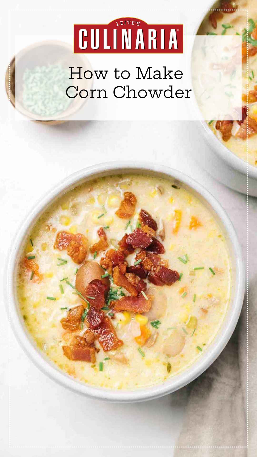 A white bowl filled with corn chowder with crispy chopped bacon sprinkled on top.