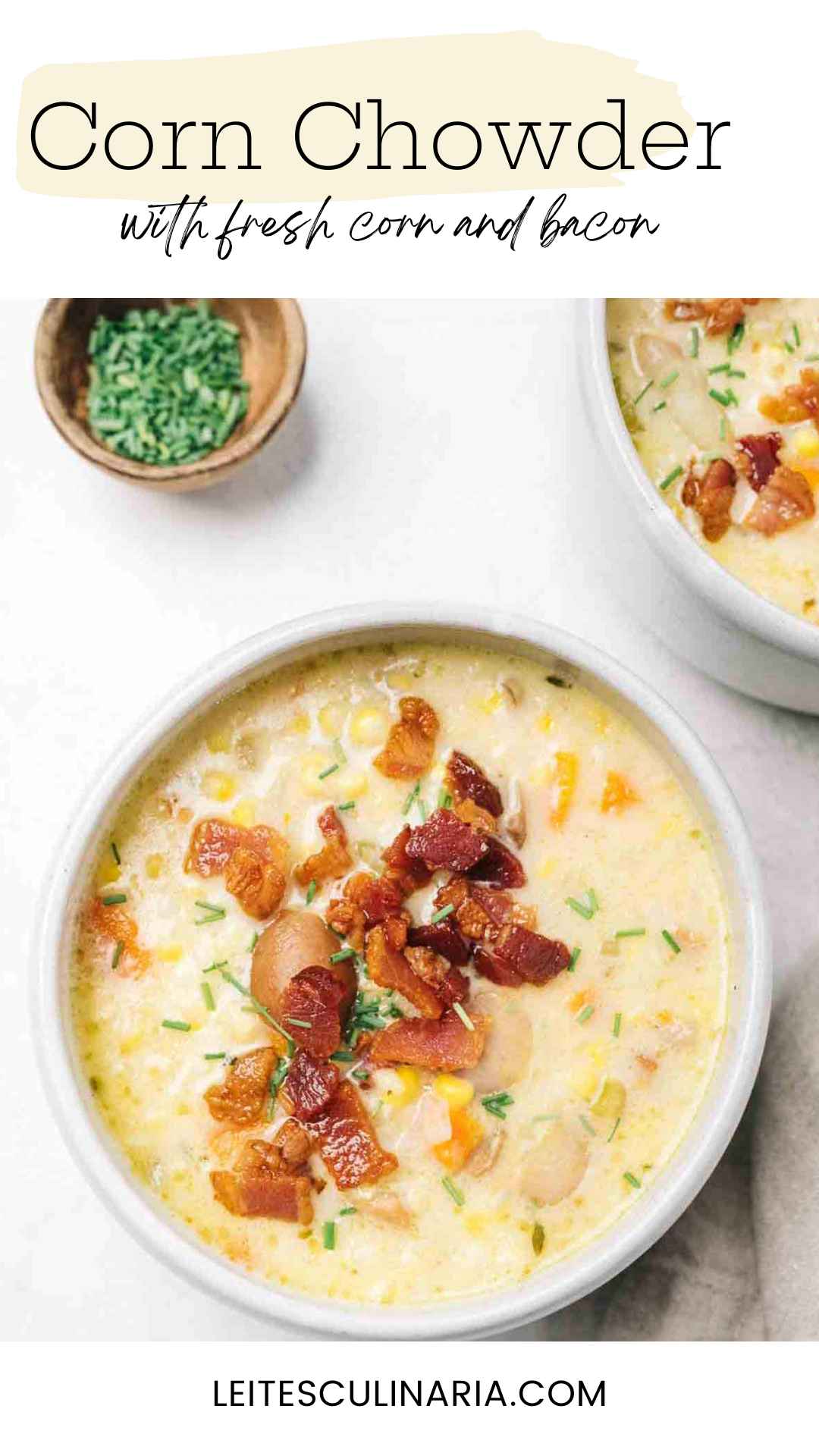 A white bowl filled with corn chowder with crispy chopped bacon sprinkled on top.