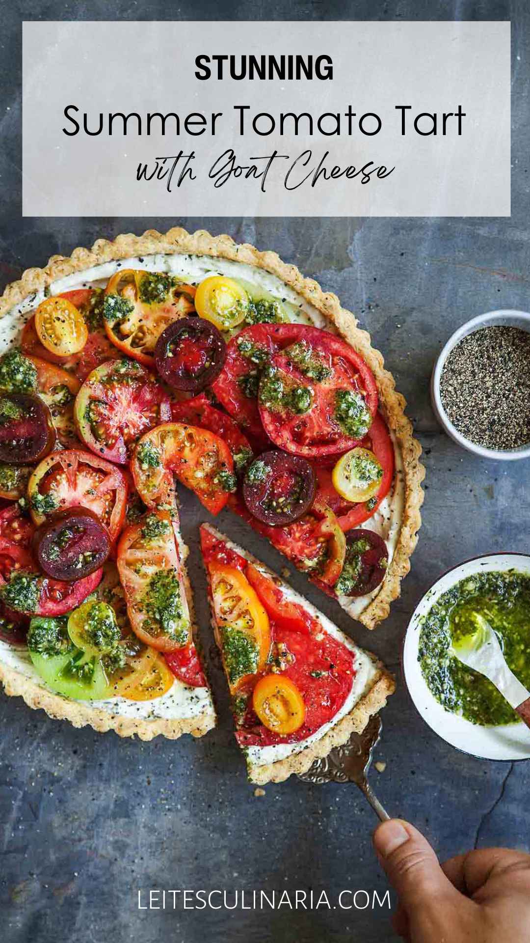 A whole tomato tart with one slice being removed from it and a bowl of pesto sauce on the side.