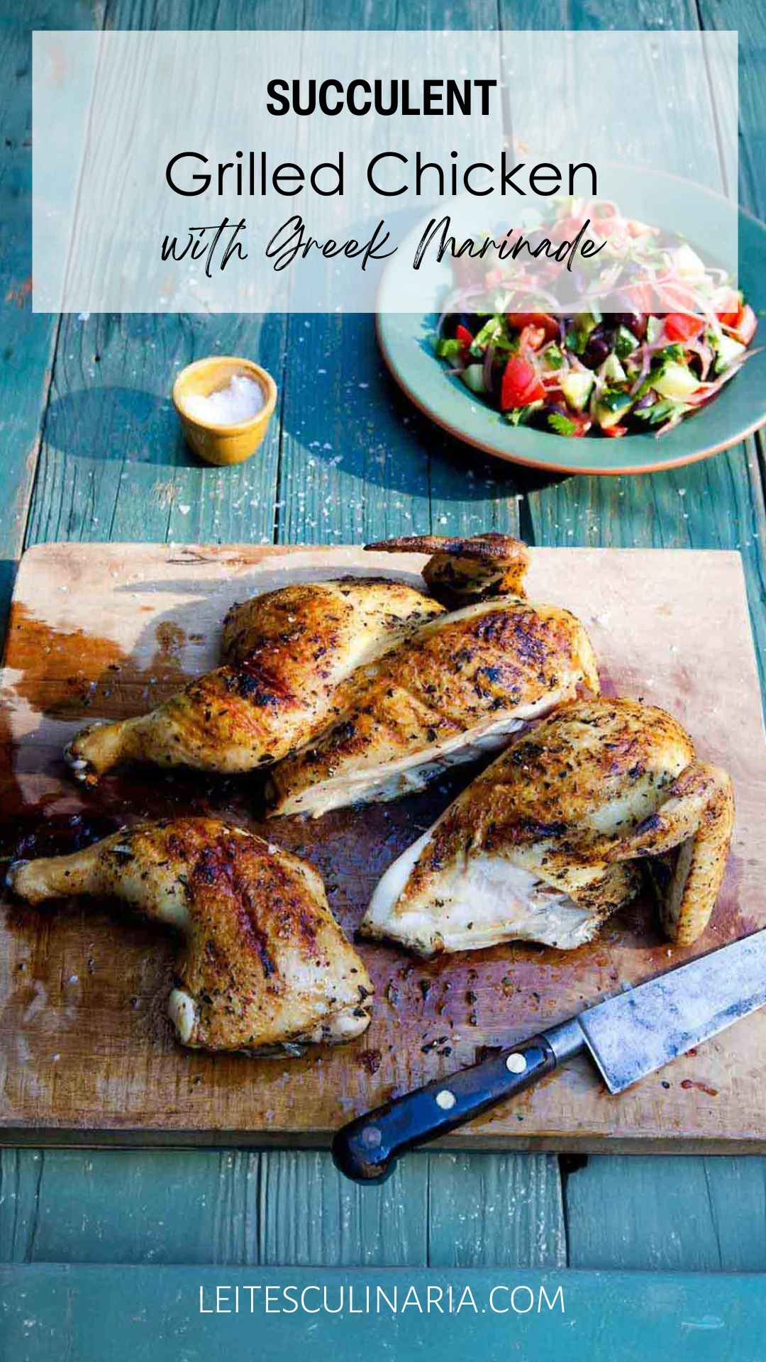 A partially carved grilled marinated chicken on a wooden board with a Greek salad nearby.