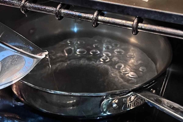 Water being added to a skillet in the oven.