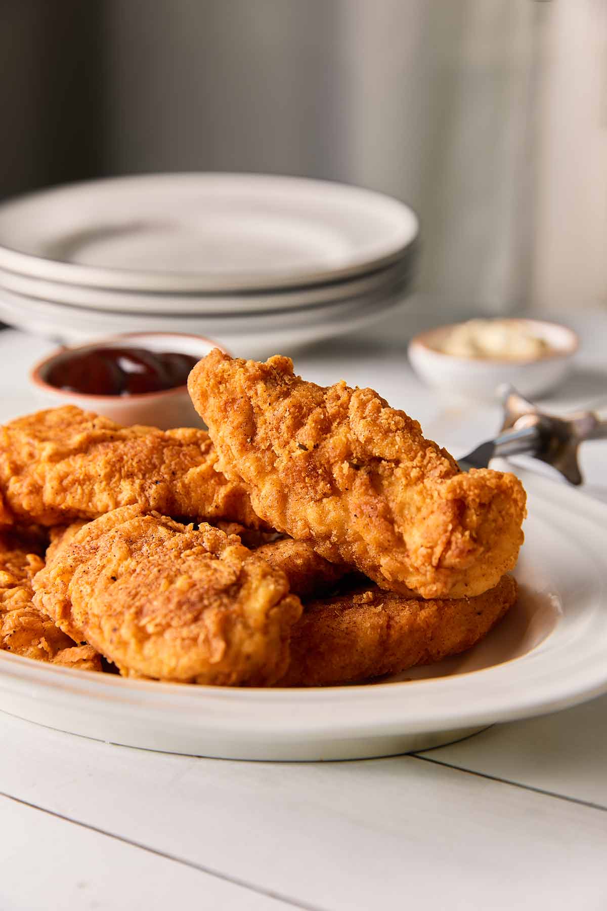 A white oval platter of pan-fried chicken tenders.