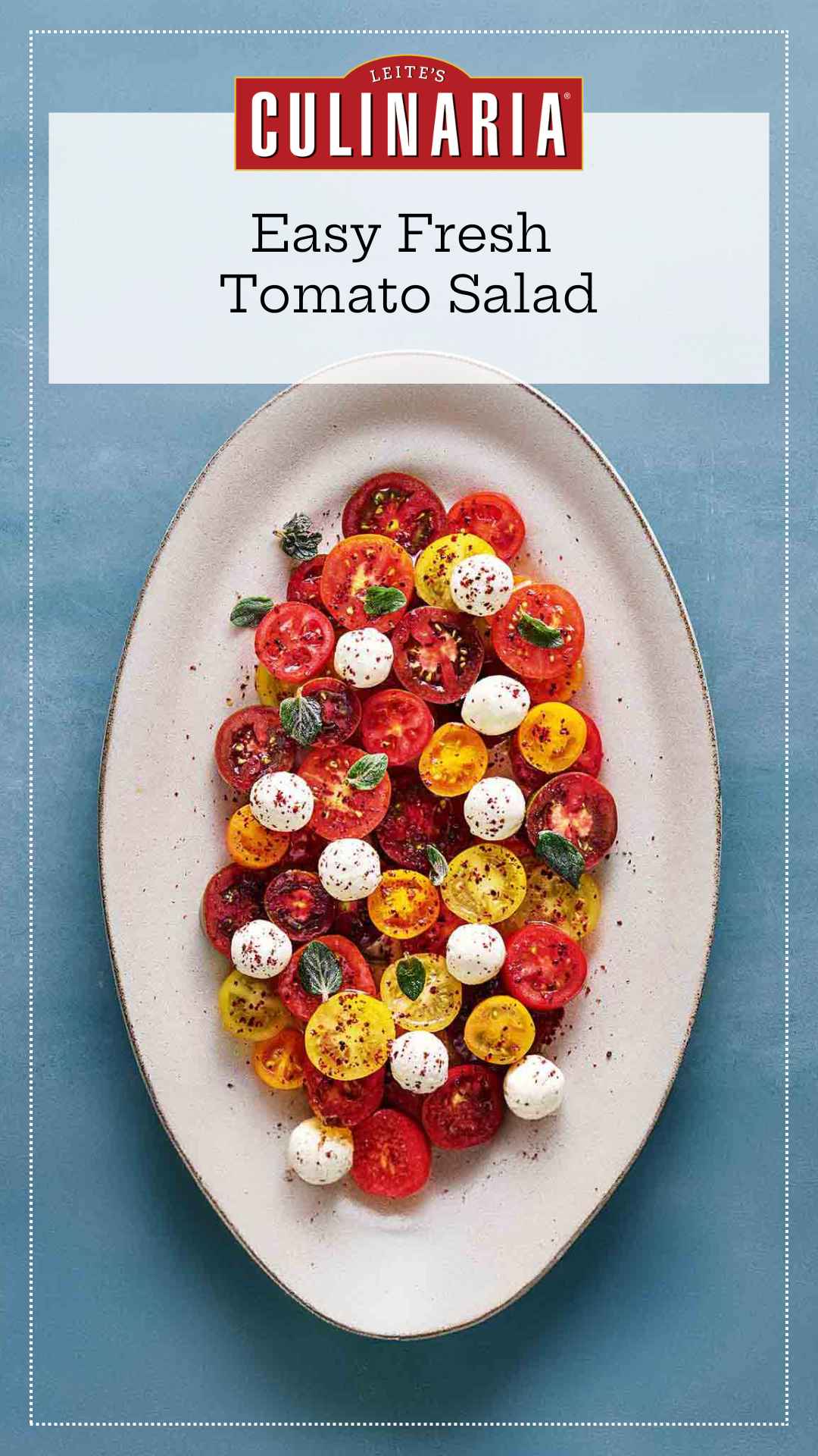 An oval platter filled with sliced tomatoes, balls of labneh, fresh herbs, and a dressing.