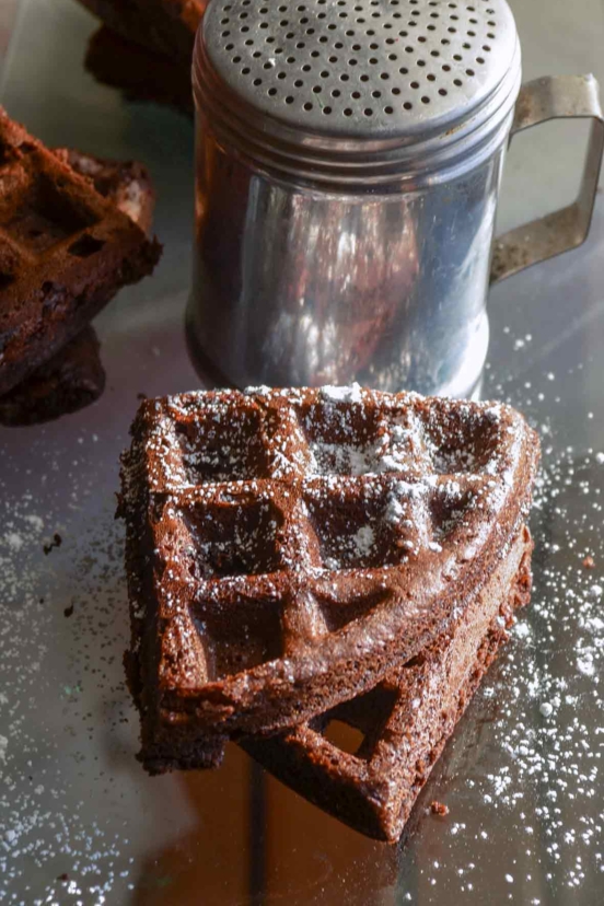 Two dark chocolate waffles dusted with confectioners' sugar.