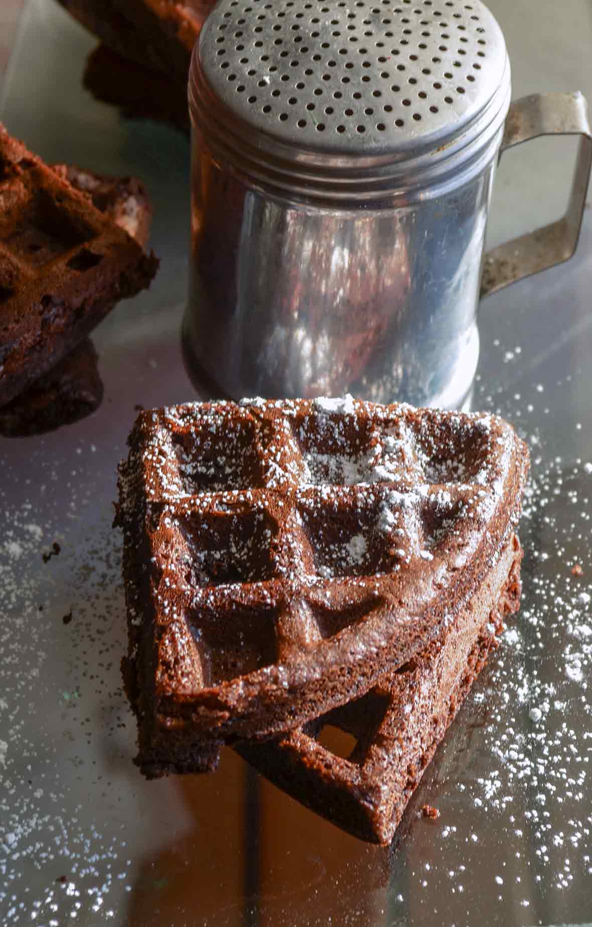 Two dark chocolate waffles dusted with confectioners' sugar.