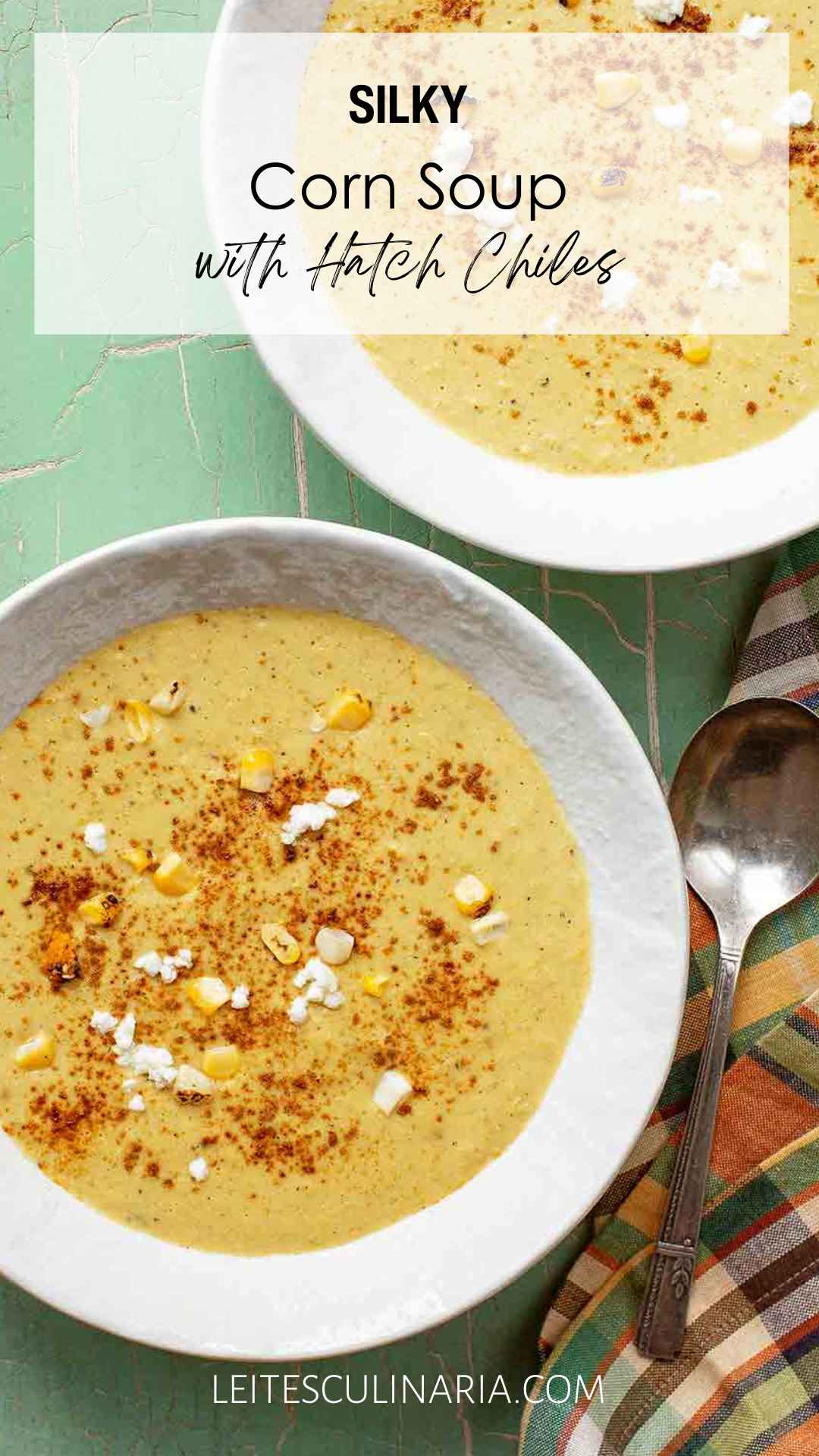 Two bowls of corn soup with fresh corn kernels, goat cheese, and paprika on top.