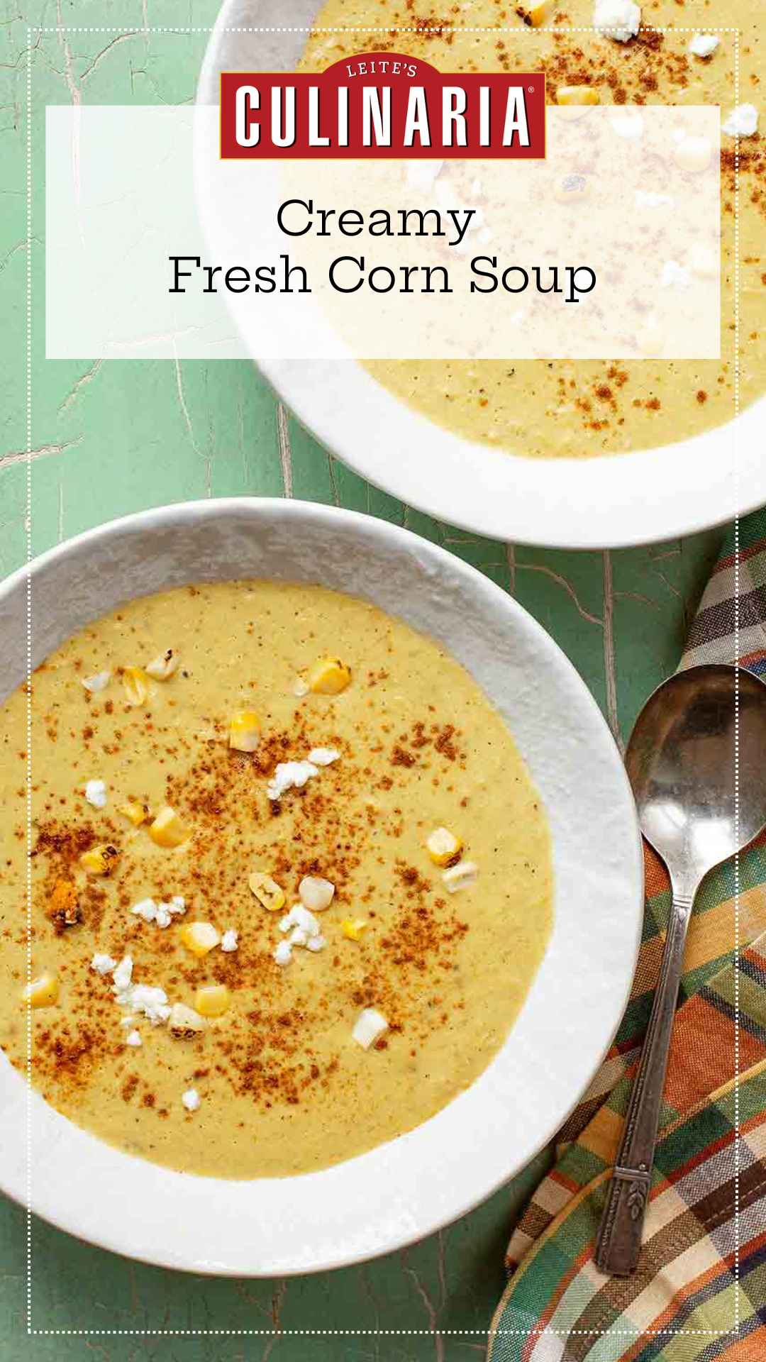 Two bowls of corn soup with fresh corn kernels, goat cheese, and paprika on top.