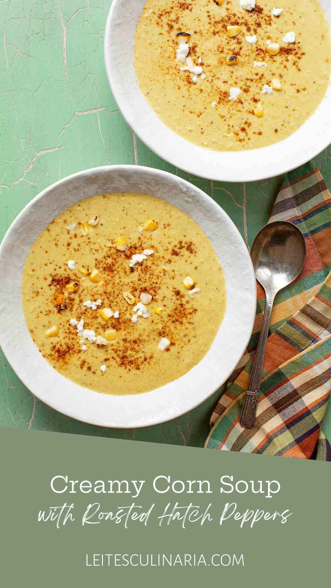 Two bowls of corn soup with fresh corn kernels, goat cheese, and paprika on top.