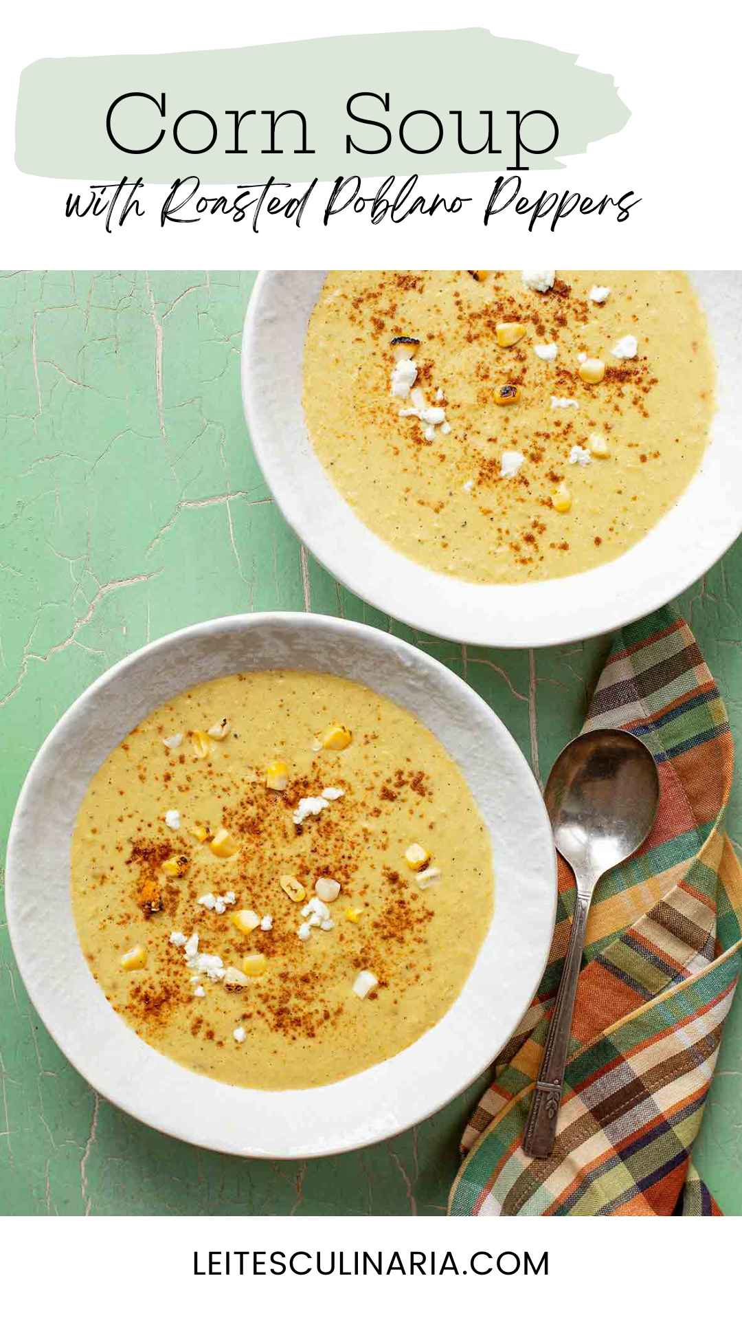 Two bowls of corn soup with fresh corn kernels, goat cheese, and paprika on top.