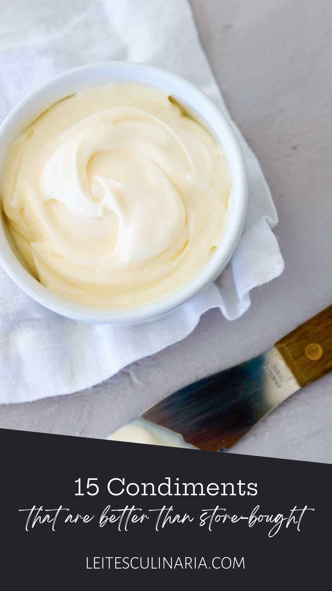 A bowl of homemade mayonnaise on a white cloth with a knife on the side.