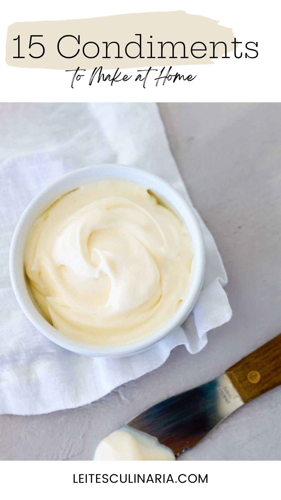 A bowl of homemade mayonnaise on a white cloth with a knife on the side.