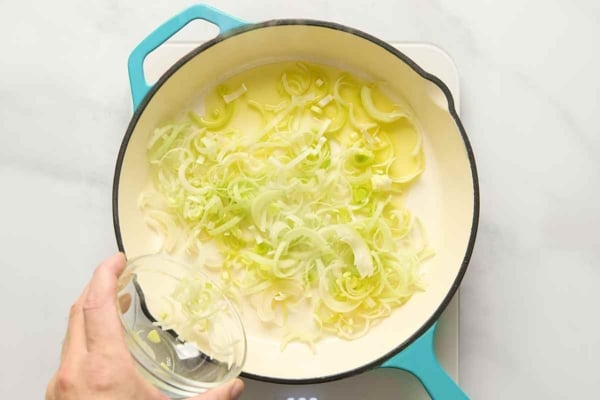 Oil and leeks cooking in a skillet.