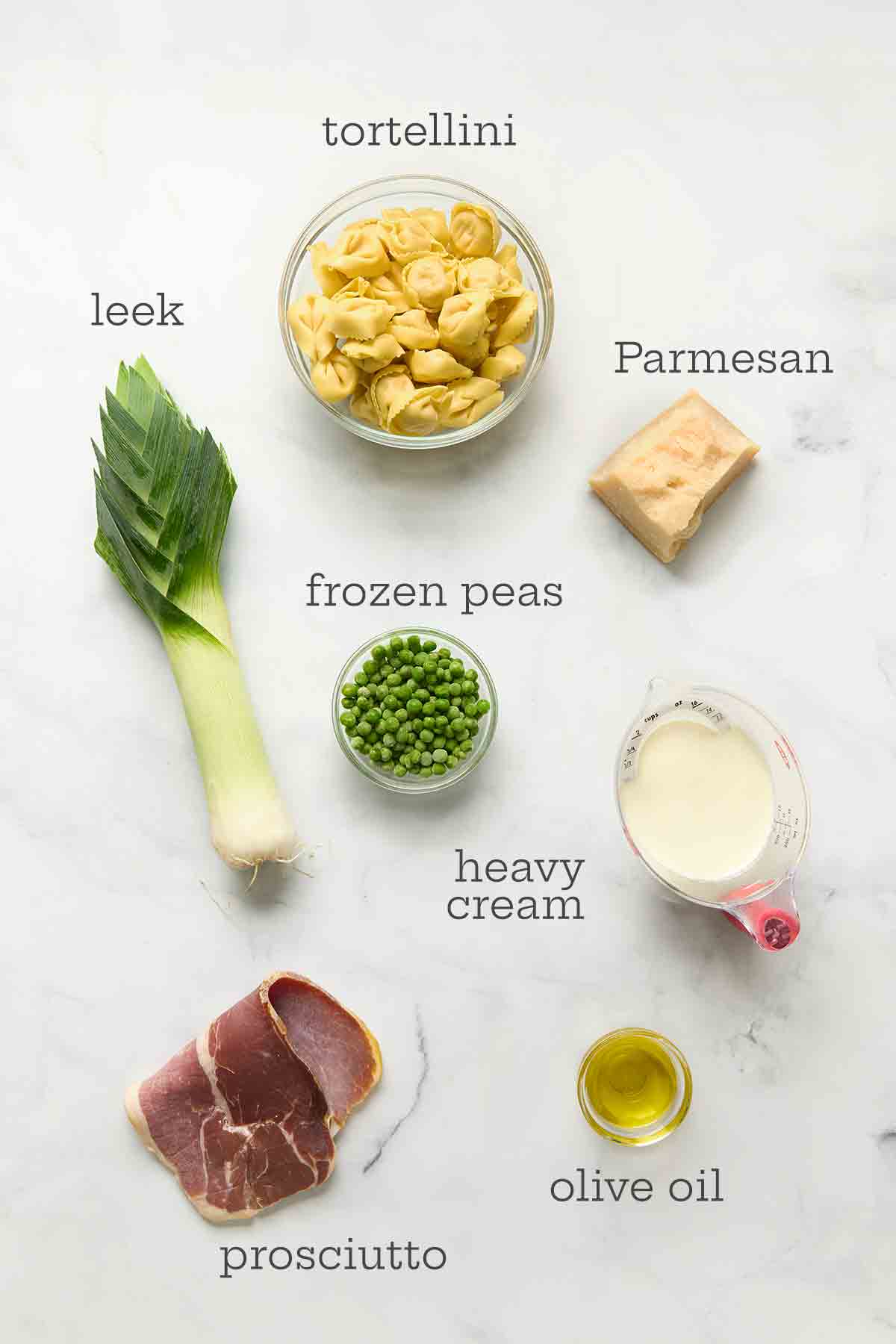 Ingredients for one-pot tortellini--tortellini, leek, Parmesan, peas, cream, oil, and prosciutto.