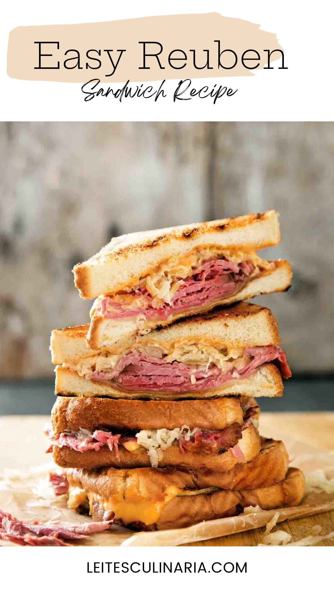 Quartered sections of a reuben sandwich stacked on top of each other on a wooden cutting board.