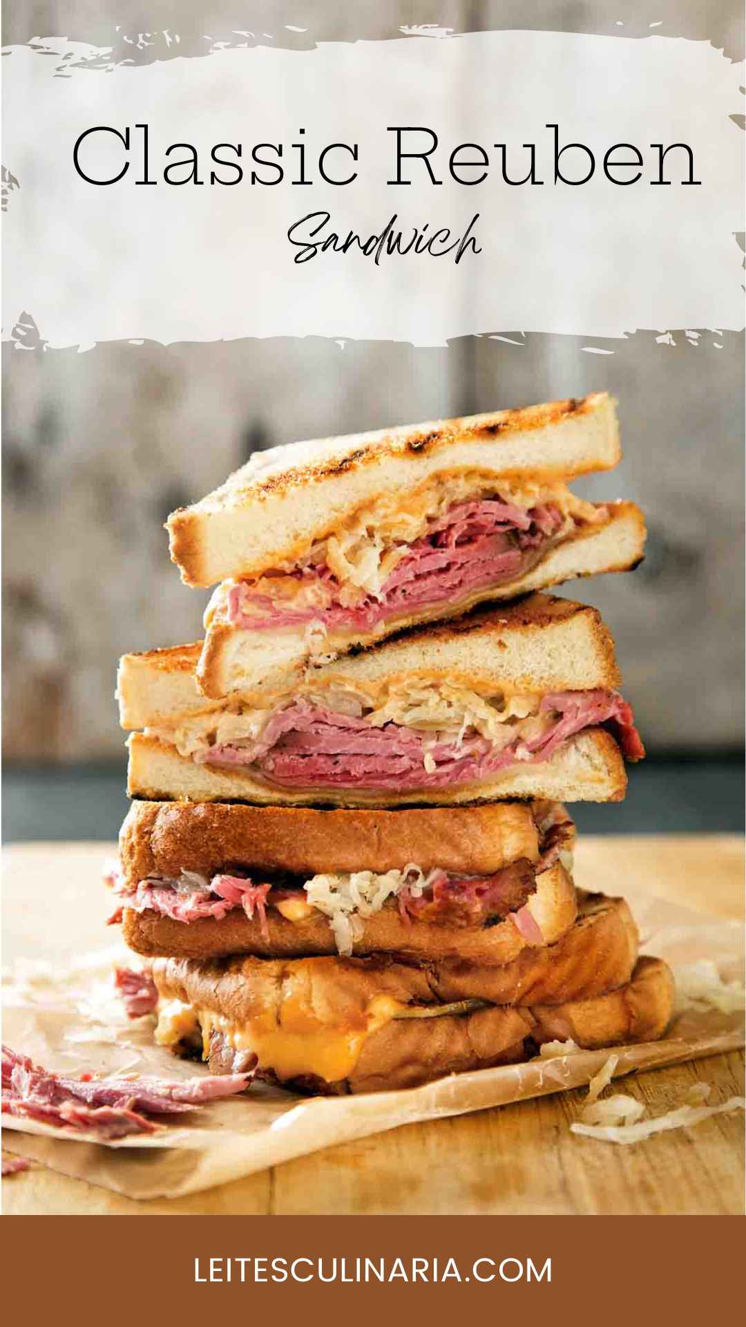 Quartered sections of a reuben sandwich stacked on top of each other on a wooden cutting board.