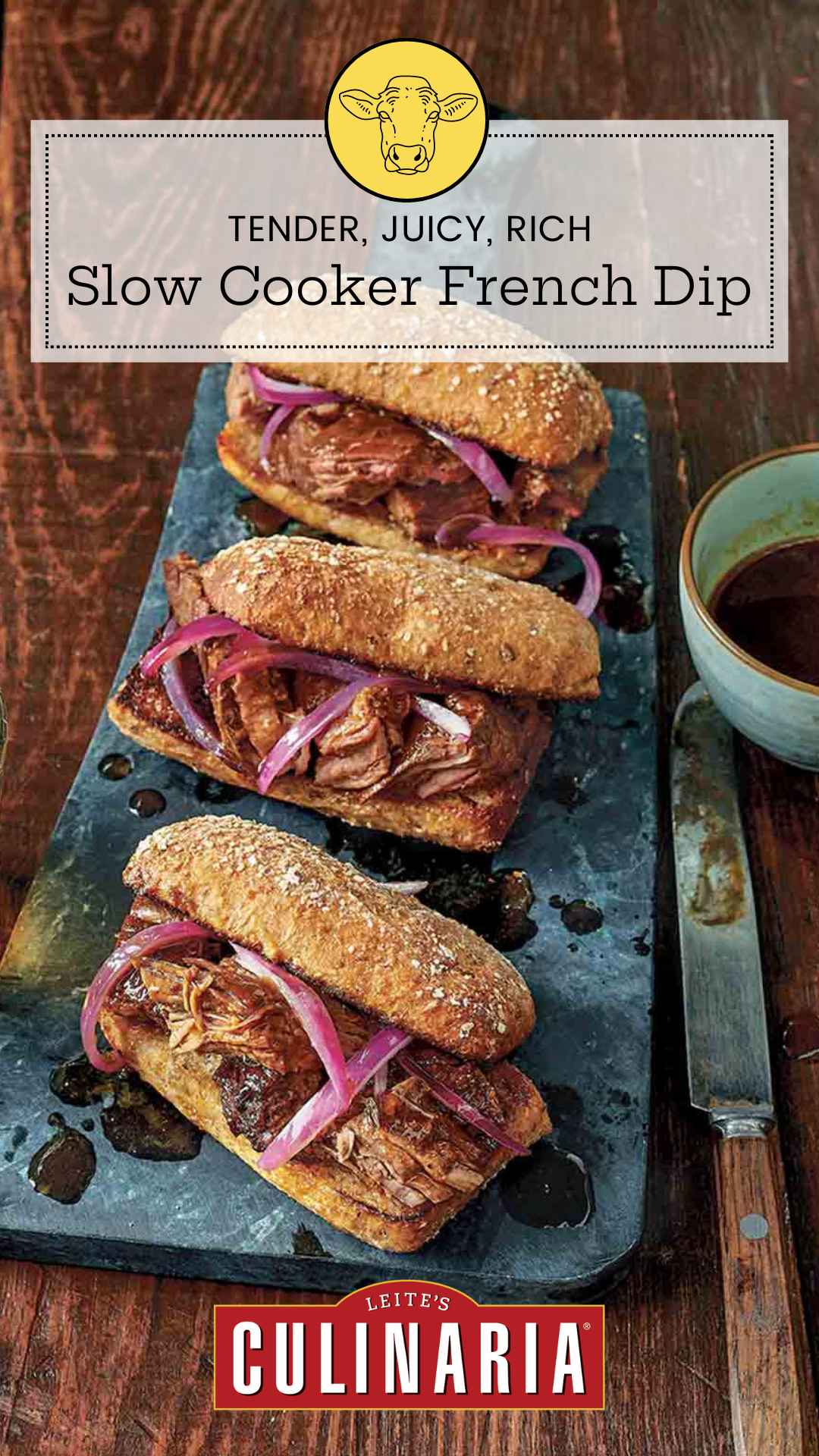 Three slow cooker French dip sandwiches with onions on serving platter with au jus on the side.