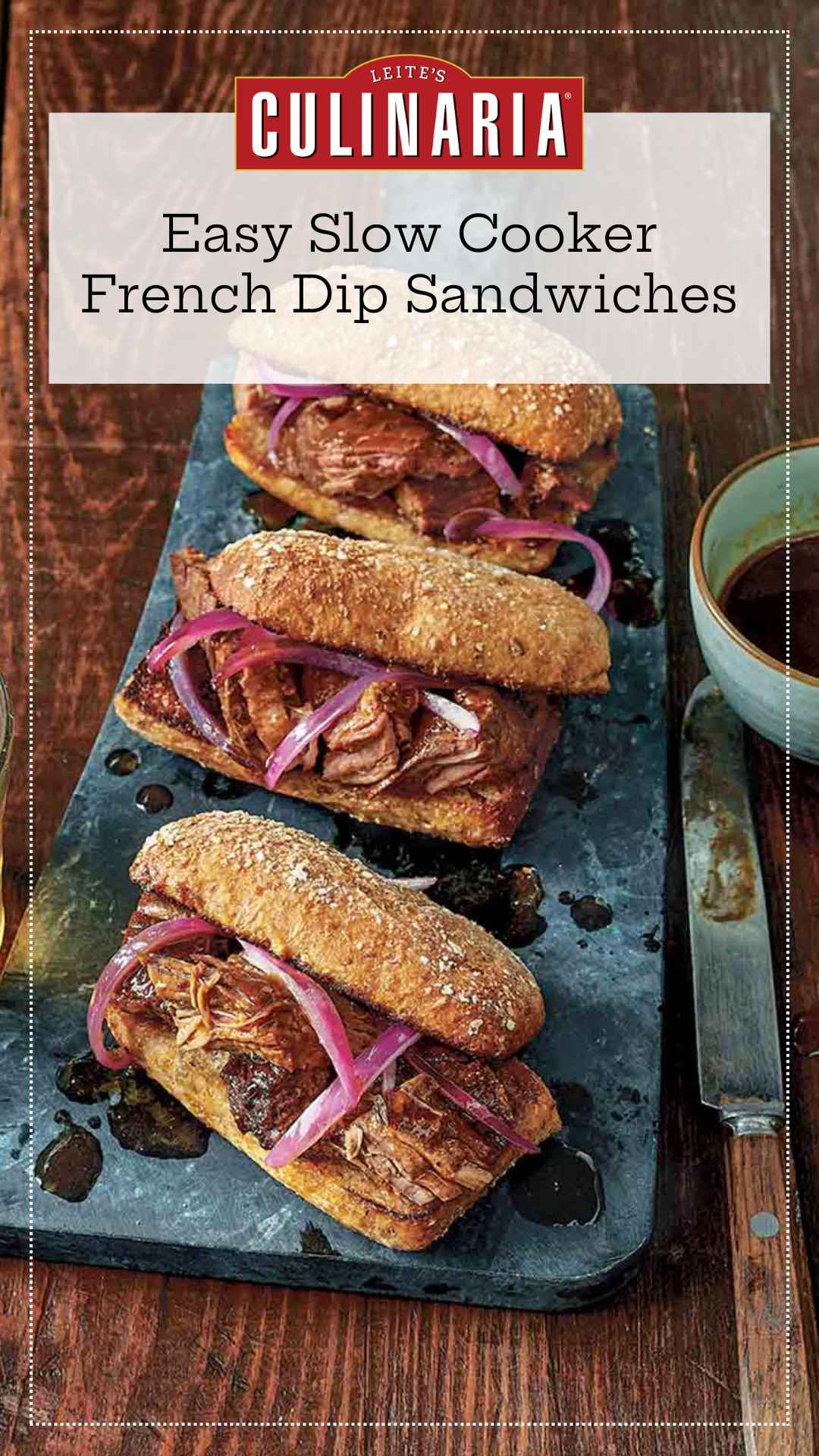 Three slow cooker French dip sandwiches with onions on serving platter with au jus on the side.