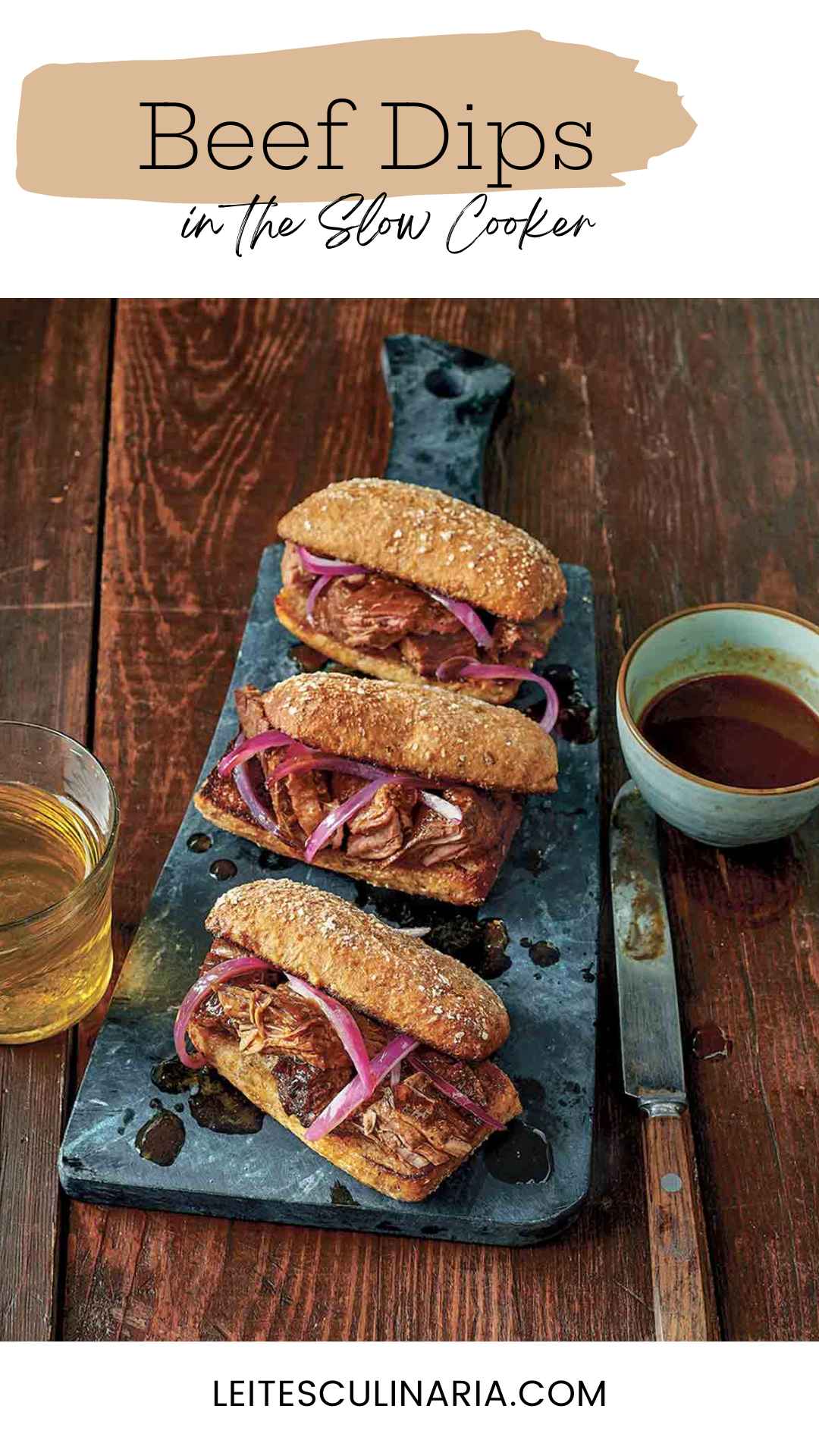 Three slow cooker French dip sandwiches with onions on serving platter with au jus on the side.