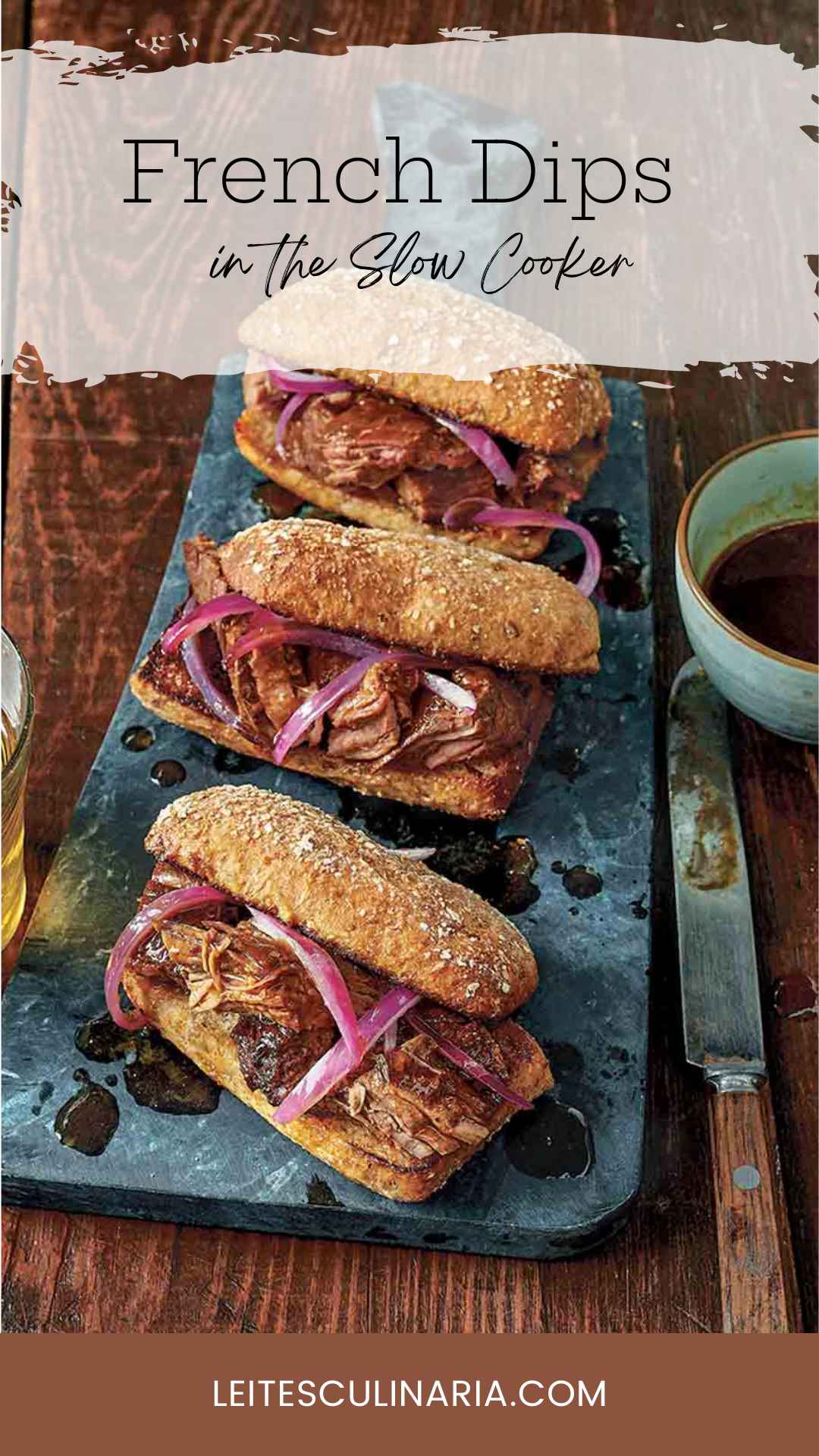 Three slow cooker French dip sandwiches with onions on serving platter with au jus on the side.