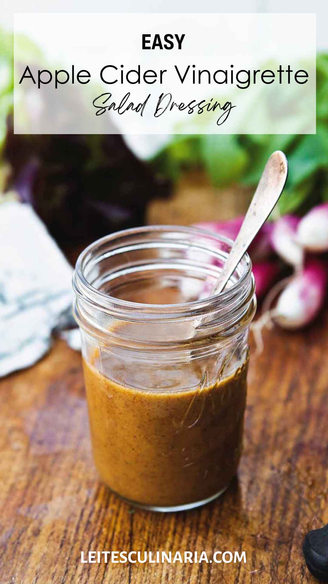 Small canning jar with spoon standing inside filled with apple cider vinaigrette.