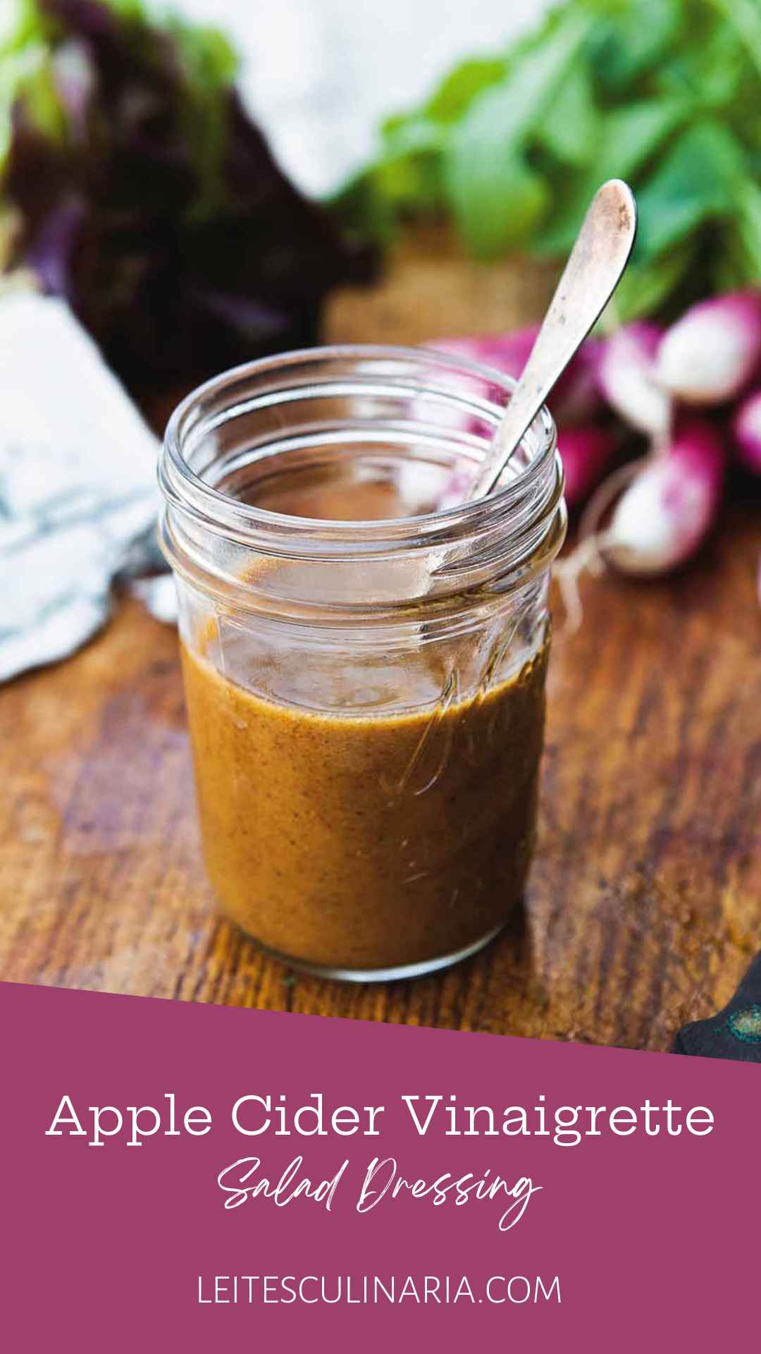 Small canning jar with spoon standing inside filled with apple cider vinaigrette.