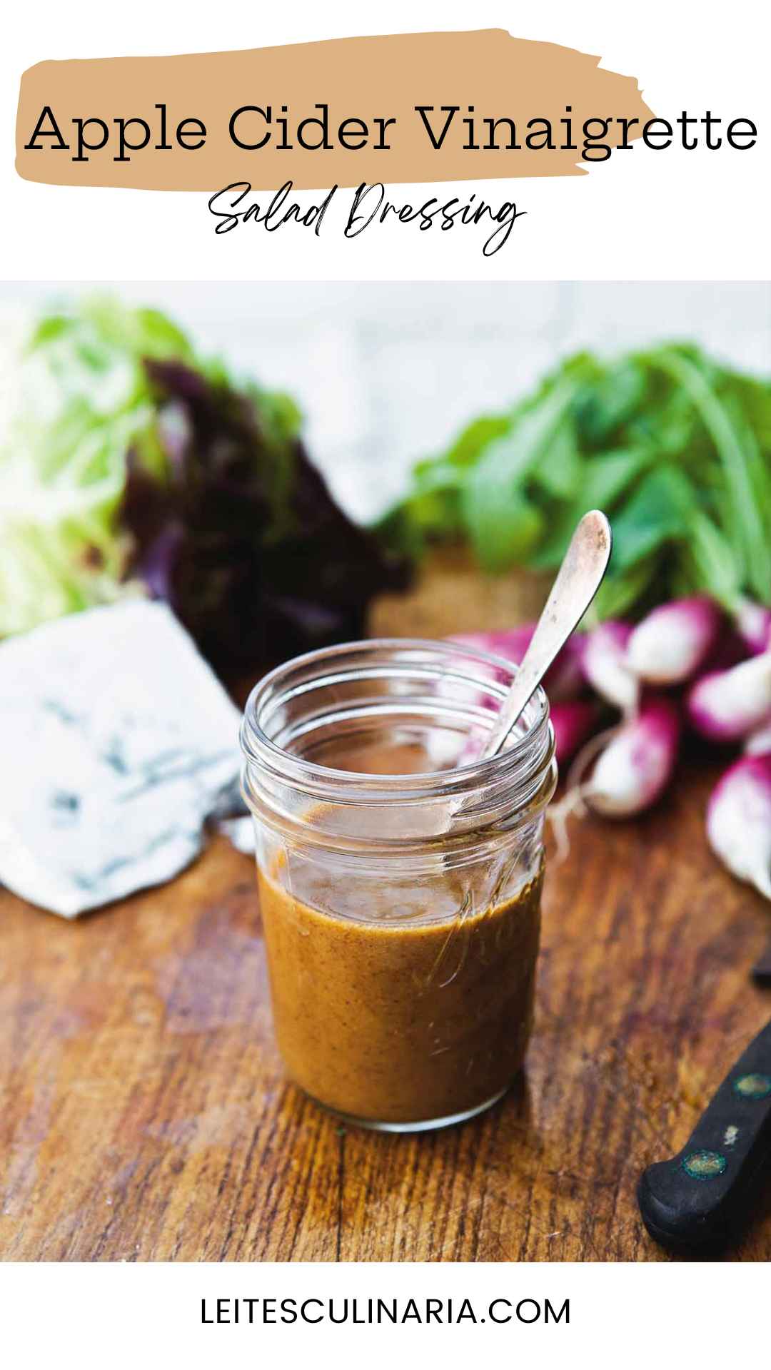 Small canning jar with spoon standing inside filled with apple cider vinaigrette.