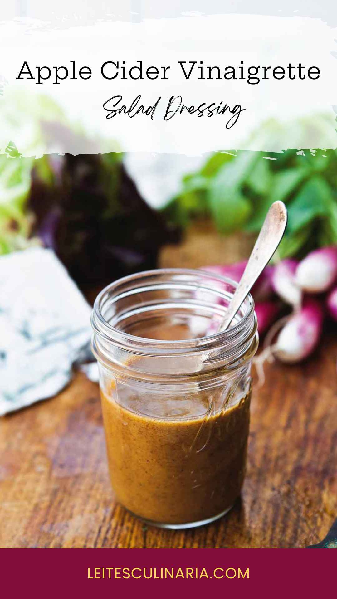 Small canning jar with spoon standing inside filled with apple cider vinaigrette.