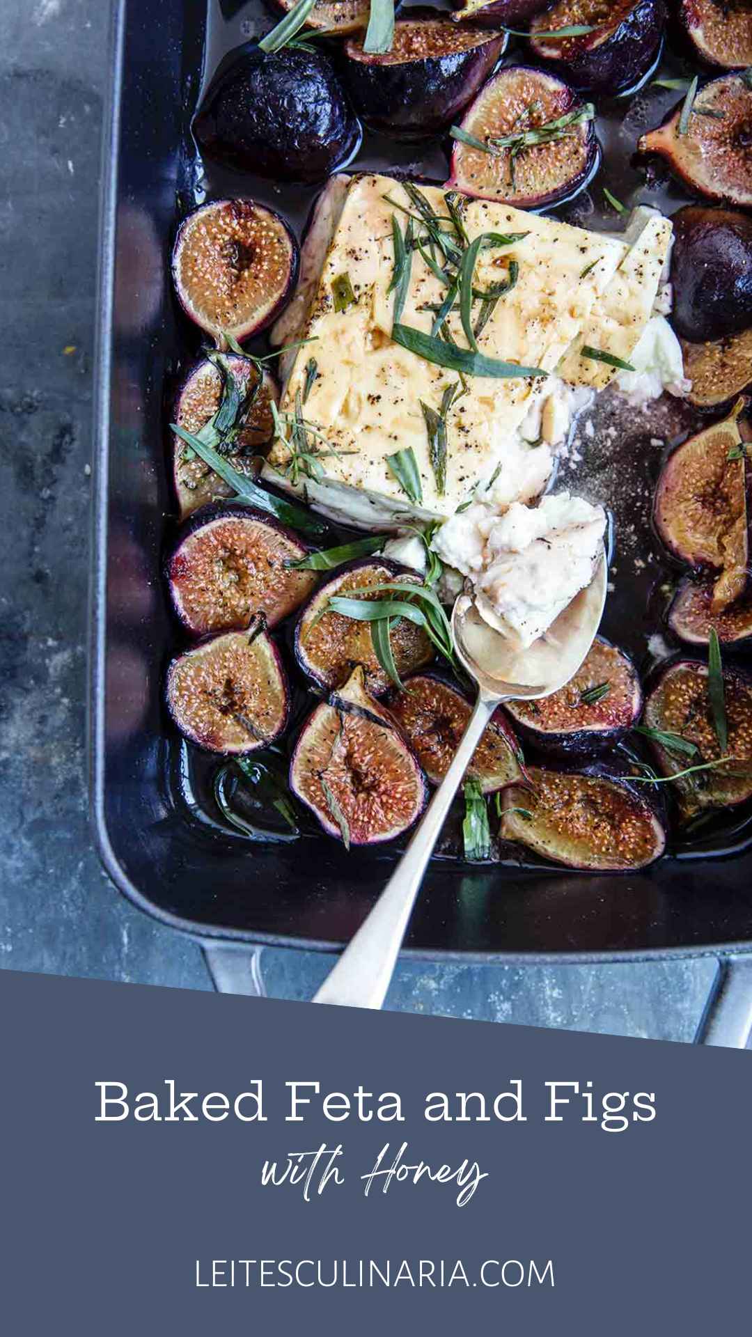 A rectangular baking dish filled with baked feta and figs, topped with fresh tarragon leaves.