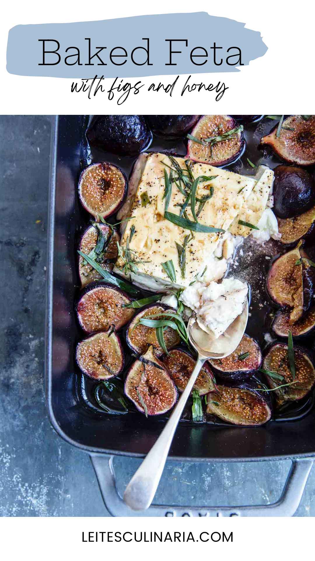 A rectangular baking dish filled with baked feta and figs, topped with fresh tarragon leaves.