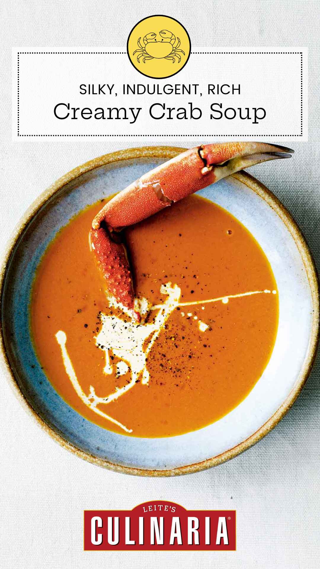 A bowl of crab soup, drizzled with cream, and sprinkled with pepper, with a crab leg sticking out of it.