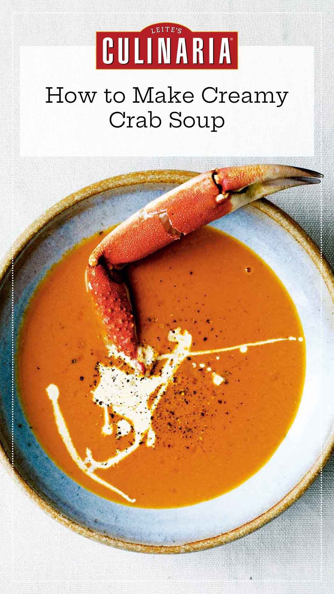 A bowl of crab soup, drizzled with cream, and sprinkled with pepper, with a crab leg sticking out of it.