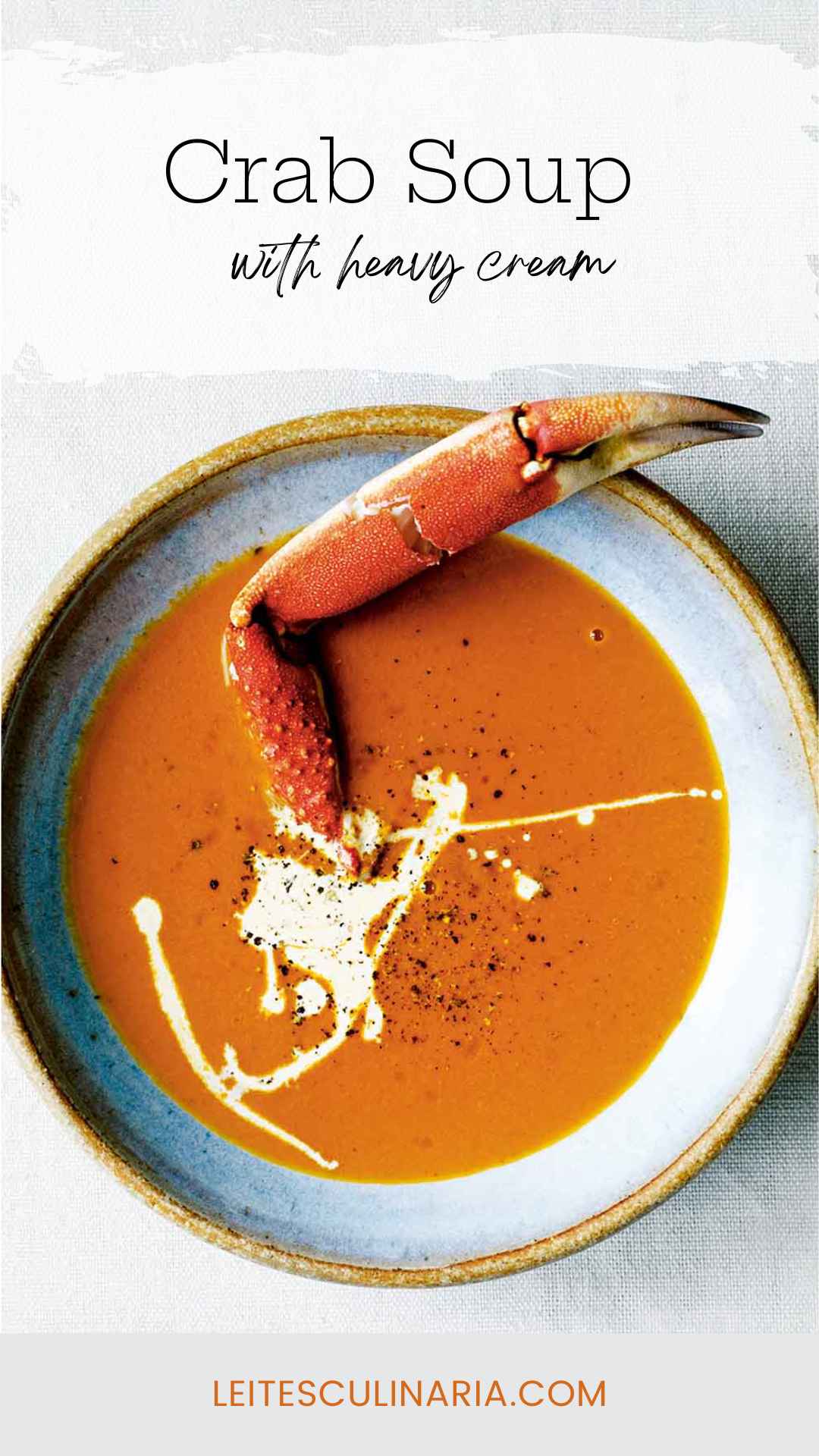 A bowl of crab soup, drizzled with cream, and sprinkled with pepper, with a crab leg sticking out of it.