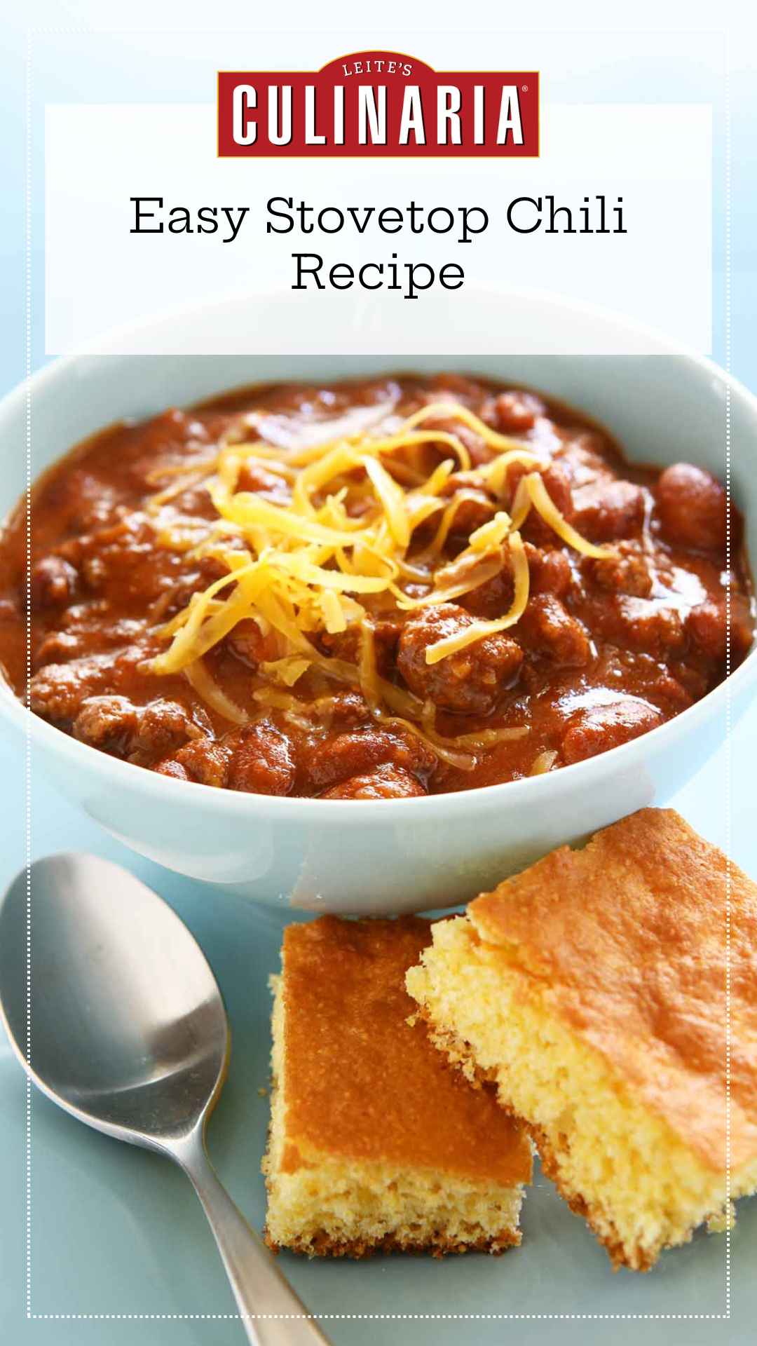 A bowl of chili with shredded cheese on top and two squares of cornbread on the side.