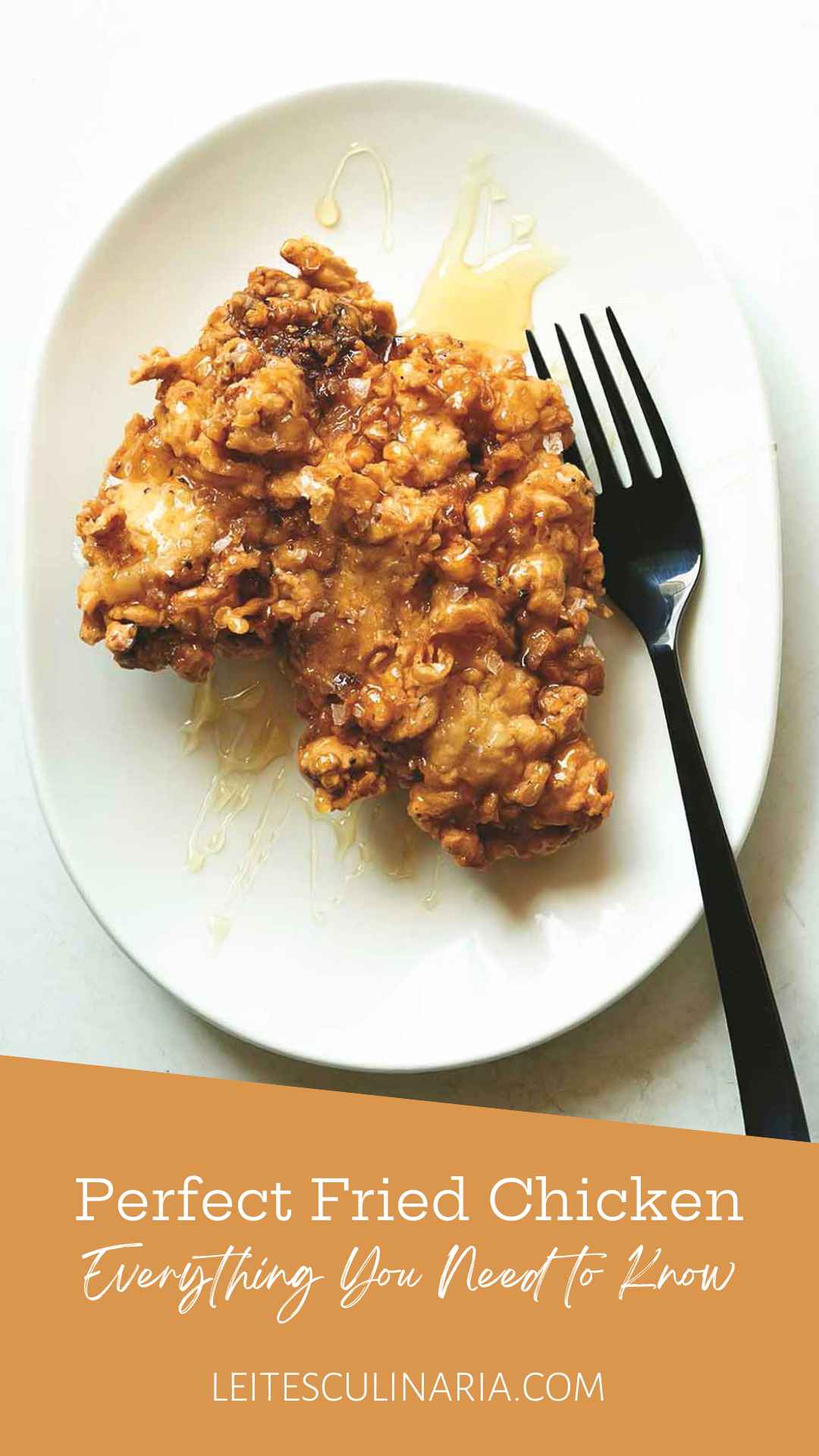 A crispy fried boneless chicken thigh drizzled with honey on a plate with a fork on the side.