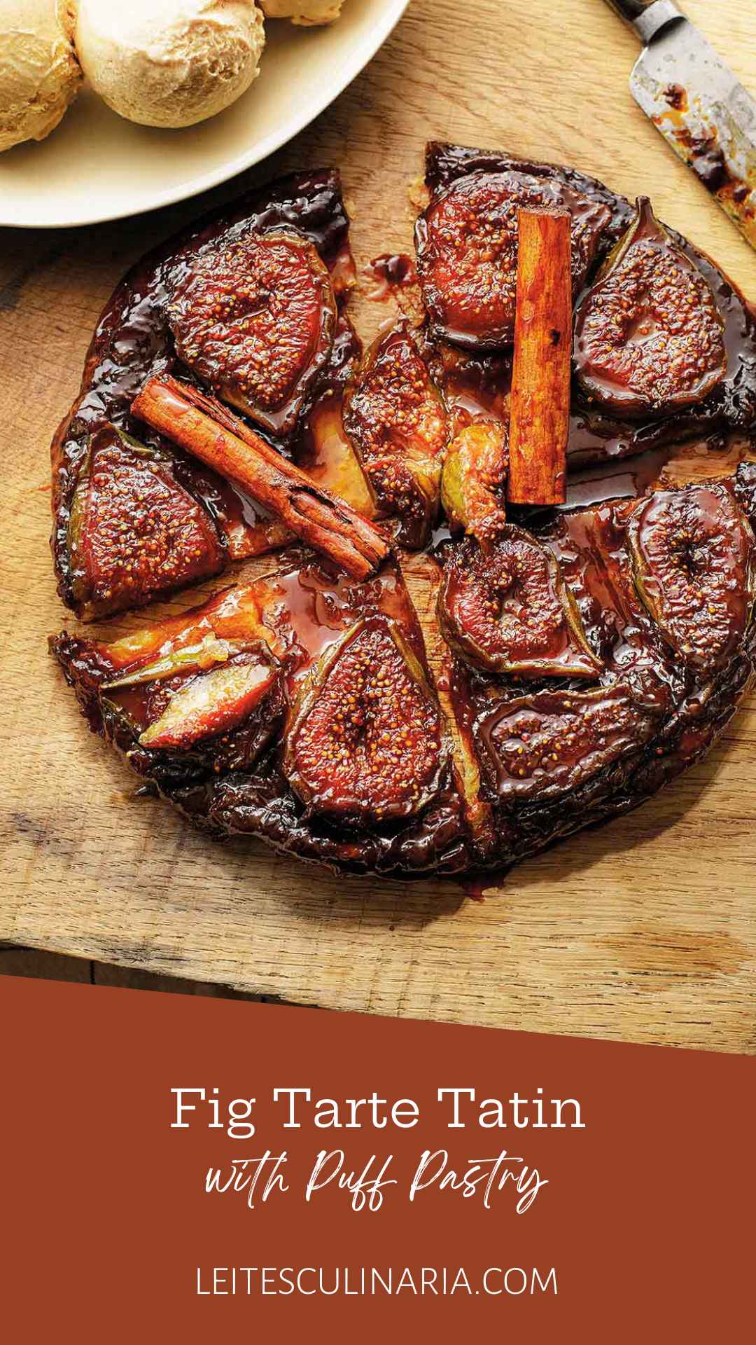 A whole fig tarte tatin topped with whole cinnamon sticks and cut into several pieces.