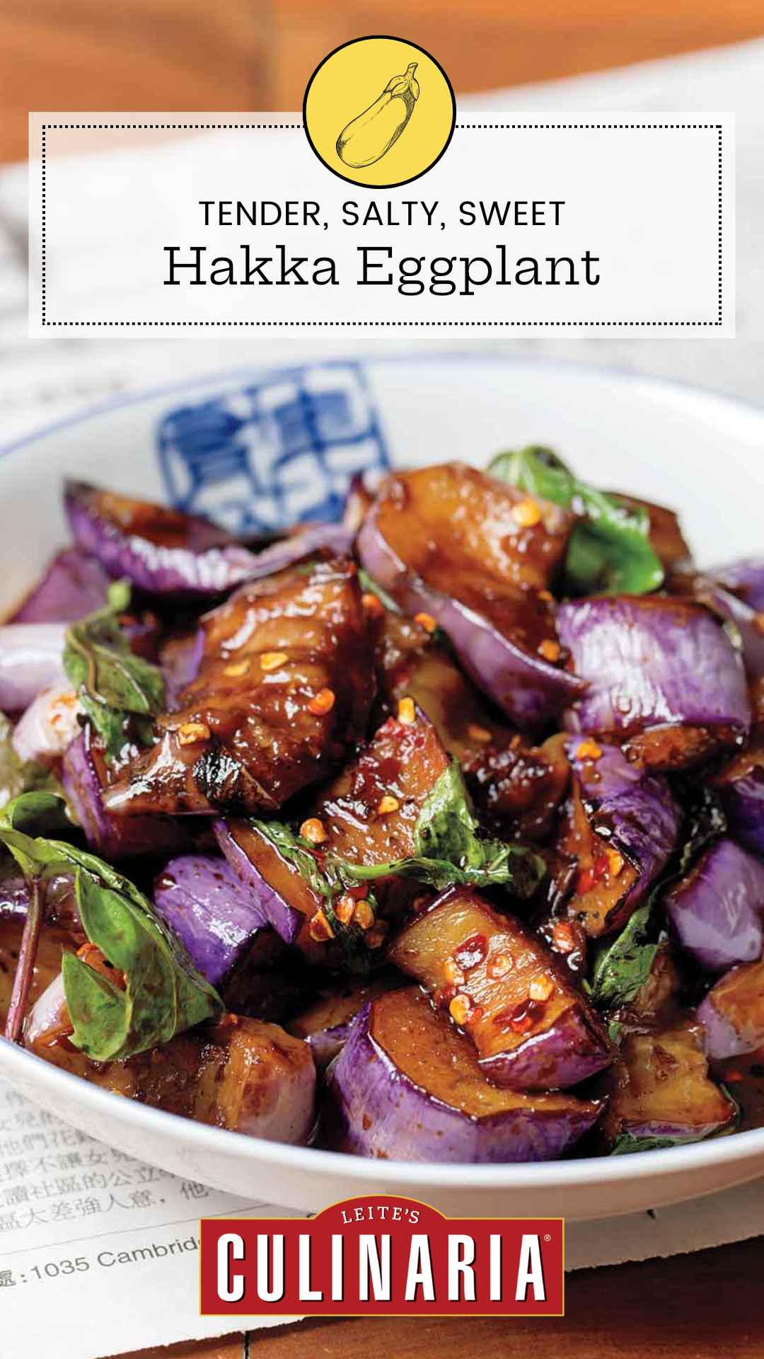 A white bowl filled with stir-fried eggplant in hakka sauce with fresh basil leaves.