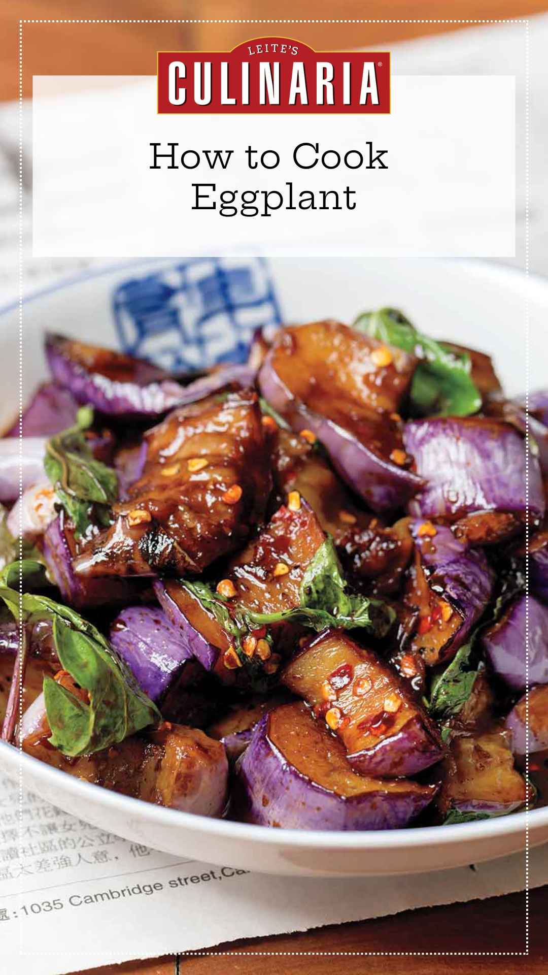 A white bowl filled with stir-fried eggplant in hakka sauce with fresh basil leaves.