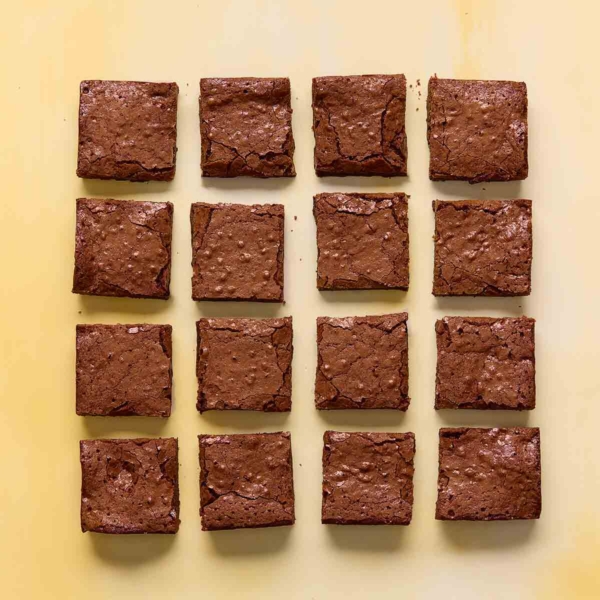 Sixteen square brownies on a yellow background.