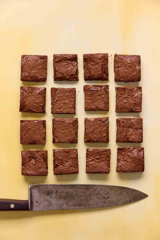 Sixteen square brownies on a yellow background.